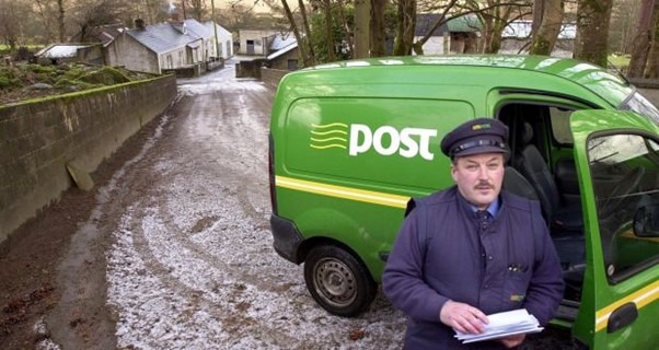 Man standing proudly in front of an An-Post van, symbolizing the success and efficiency of Eircodes in address capture and validation. Photograph: Eric Luke @ Irish Times