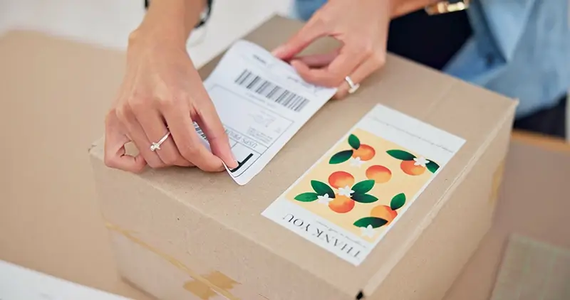 Someone putting an address label on a parcel