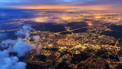 A captivating aerial night-time image of a city illuminated with lights, showcasing the intricate web of streets and thoroughfares. The glowing cityscape vividly represents the interconnectedness and complexity of urban landscapes, symbolizing the diverse and intricate nature of global address systems that the blog discusses in the context of localization in user experience.