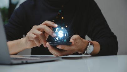 A vibrant image showcasing a futuristic fintech interface displayed on a mobile phone, with holographic elements symbolizing advanced financial technologies. The phone is held by a professional, indicating the accessibility and innovation in fintech services enabled by Autoaddress's address intelligence solutions.